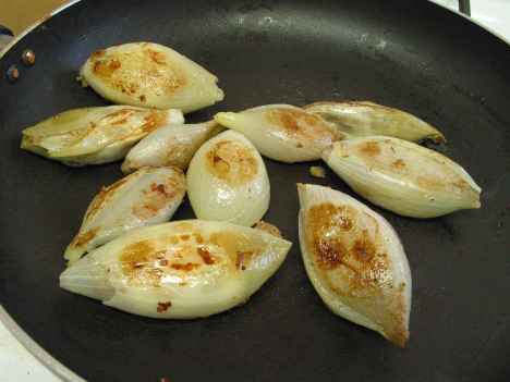 Browning the stuffed onions in a pan