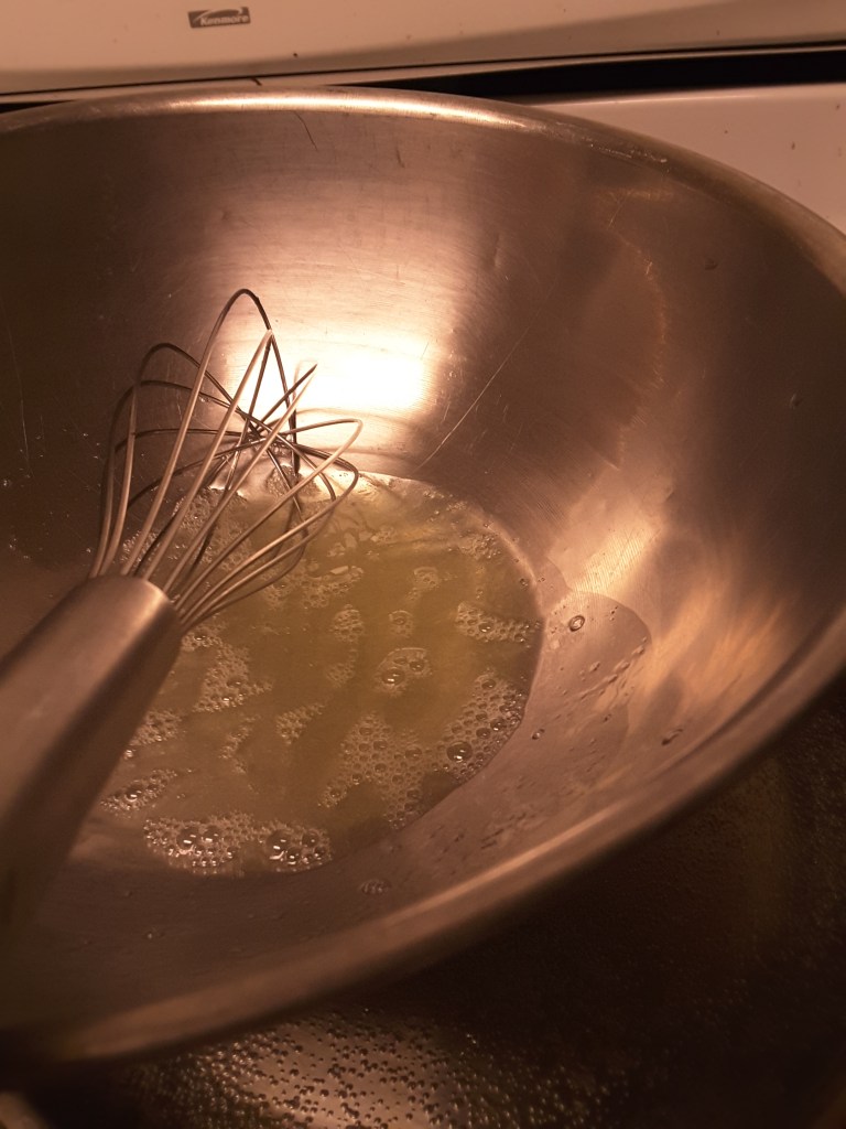 Beating egg whites with sugar and water over a pan of simmering water